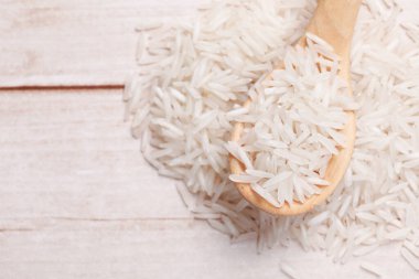 Çiğ basmati pilavı ve kaşık beyaz ahşap masa, üst manzara. Metin için boşluk