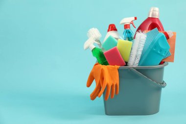 Açık mavi arkaplanda kovadaki farklı temizlik ürünleri, metin için boşluk
