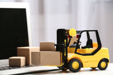 Oyuncak forklift ve dizüstü bilgisayarın yanındaki kutular. Lojistik ve toptan satış kavramı