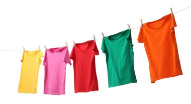 Beyaz arka planda çamaşır ipinde kuruyan farklı parlak tişörtler.