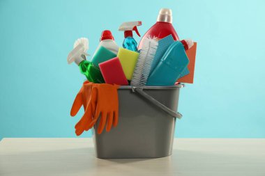 Tahta masadaki kovadaki farklı temizlik ürünleri açık mavi arka planda