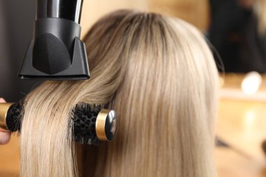 Kuaför kuaför kuaförde müşterinin saçını kurutuyor.