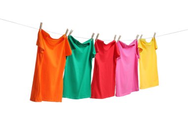 Beyaz arka planda çamaşır ipinde kuruyan farklı parlak tişörtler.