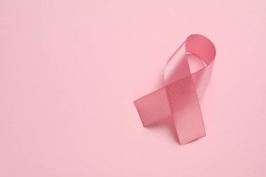 Renk arkaplanı üzerine pembe kurdele, metin için üst görünüm ve boşluk. Göğüs kanseri farkındalığı