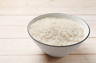 Beyaz ahşap masadaki kase içinde çiğ basmati pilavı, metin için yer.