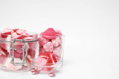 Cam kavanozda farklı tatlı pembe şekerler ve beyaz arka planda kaseler, metin için yer