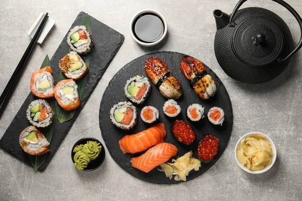 Flat lay composition with delicious sushi rolls on light grey table