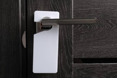 Kapalı ahşap kapı. Metal sapında boş askı var. Yakın plan.