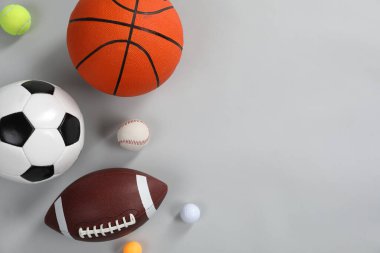 Gri arka planda, düz zeminde birçok farklı spor topu var. Metin için boşluk
