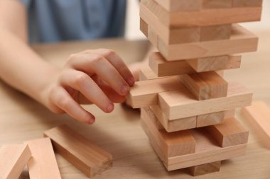 Çocuk içeride ahşap masada Jenga oynuyor, yakın plan.