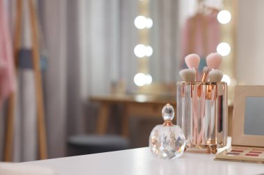 Makyaj odasındaki beyaz masaya fırça, göz falı ve parfüm seti, mesaj için yer