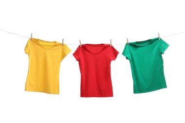 Beyaz arka planda çamaşır ipinde kuruyan farklı parlak tişörtler.