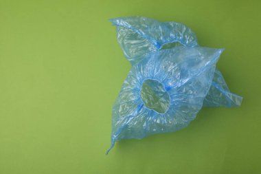 Yeşil arka planda bir çift mavi tıbbi ayakkabı kılıfı, üst manzara. Metin için boşluk