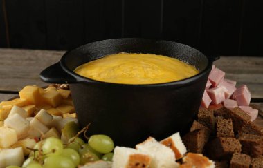 Erimiş peynirli fondü kabı ve masada farklı ürünler, yakın plan.