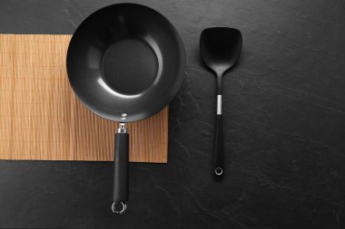 Siyah metal wok ve spatula koyu dokulu masa, üst görünüm