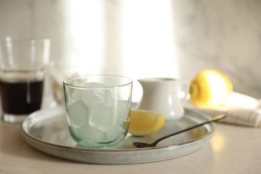 Buzlu kahve yapıyorum. Bardakta buz küpleri ve beyaz tahta masada kaşık, yakın plan.