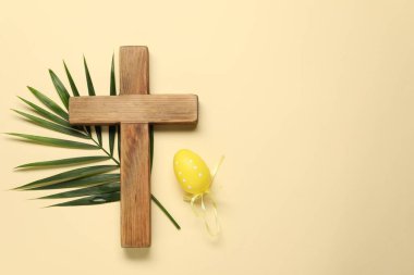 Ahşap haç, Paskalya yumurtası ve bej arka planda palmiye yaprağı, üst manzara. Metin için boşluk