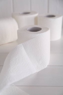 Yumuşak tuvalet kağıdı beyaz ahşap masada yuvarlanıyor.
