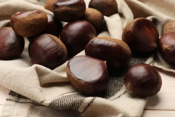 stock image Sweet fresh edible chestnuts on light wooden table, closeup