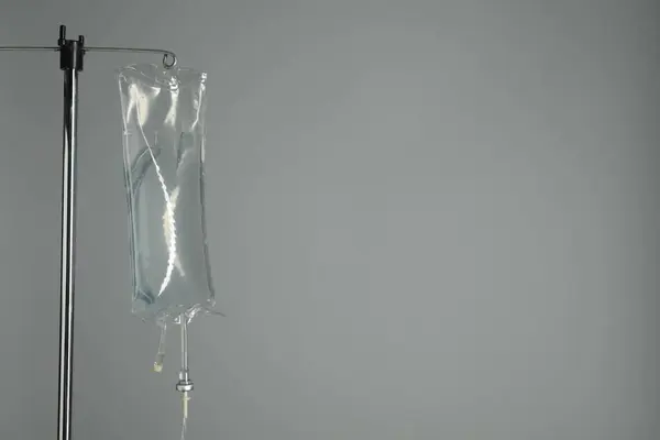 IV infusion set on pole against grey background. Space for text