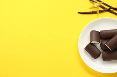 Krem peynirli gofret, vanilyalı kaplar ve sarı arka planda çiçek, üst manzara. Metin için boşluk