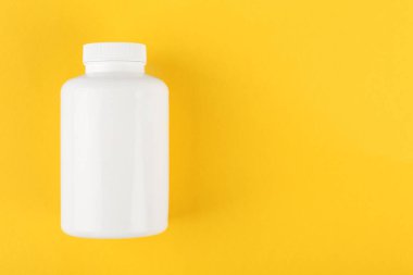 Sarı arka planda beyaz bir tıbbi şişe. Metin için boşluk