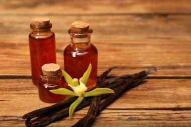 Aromatik vanilya özü, kapsüller ve çiçek ahşap masada, yakın plan. Metin için boşluk