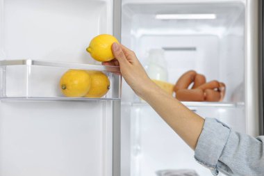Limonu buzdolabından çıkaran genç kadın, yakın plan.