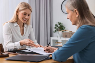 Üst düzey kadın avukatın ofisinde belge imzalıyor.