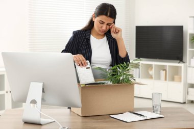 İşsizlik sorunu var. Ofisinde kişisel eşyalarıyla dolu bir kutuyla hayal kırıklığına uğramış bir kadın.