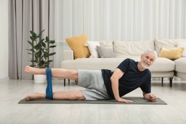 Son sınıf öğrencisi evde spor yaparken lastik bant takıyor.