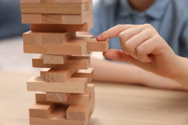 Çocuk içeride ahşap masada Jenga oynuyor, yakın plan.