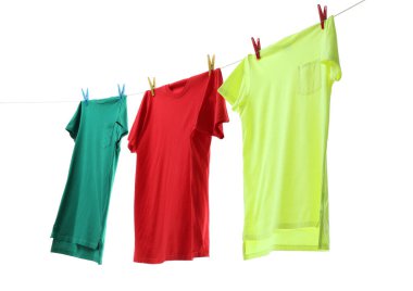 Çamaşır ipinde kurumuş renkli tişörtler beyazda izole edilmiş.