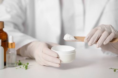 Beyaz masada kavanoz testi kozmetik ürünü olan dermatolog, seçici odak