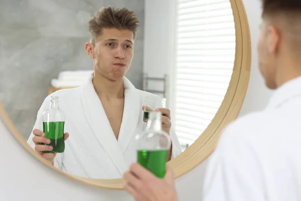 浴室の鏡の近くでマウスウォッシュを使用している若い男 — ストック写真