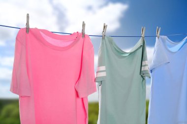 Açık havada çamaşır ipinde farklı tişörtler kuruyor.
