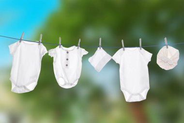 Çamaşır ipinde farklı bebek kıyafetleri kuruyor.
