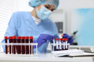 Laboratuvar testi. Beyaz masalardaki tüplerde kan örnekleri olan bir doktor.