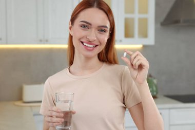 Vitamin hapı ve bir bardak suyla güzel bir genç kadın.
