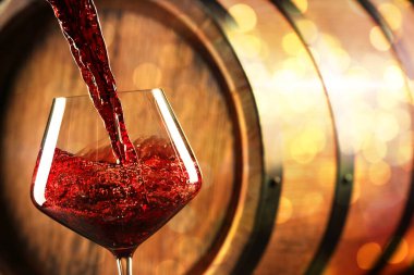 Kırmızı şarabı arka planda bulanık ışıklarla bardağa doldurmak, yakın plan. Metin için boşluk