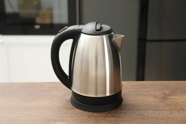 Modern electric kettle on table in kitchen