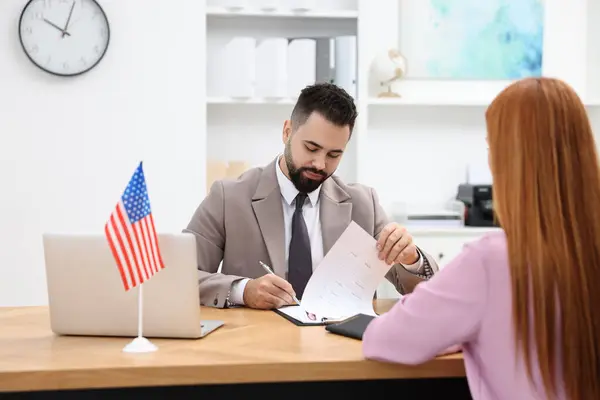 stock image Immigration to United States of America. Embassy worker approving visa application form to woman in office
