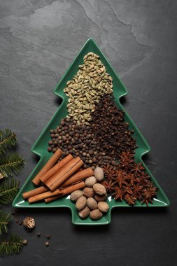 Farklı baharatlar, fındıklar ve köknar dalları koyu gri desenli masa, düz yatıyordu.