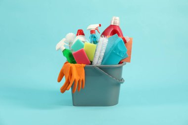 Açık mavi arka planda kovadaki farklı temizlik ürünleri