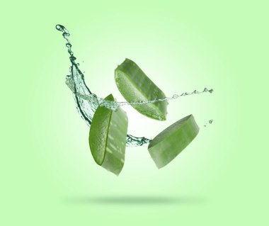Dilimlenmiş aloe vera yaprağı ve yeşil arka planda biraz meyve suyu.