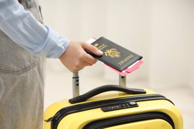 Bavullu kadın, pasaport ve arka planı bulanık biletler, yakın plan.
