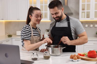 Genç ve güzel bir çift mutfakta birlikte yemek pişiriyor.