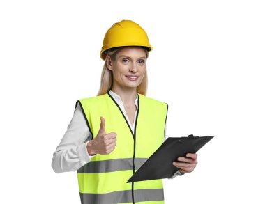 Kask takan mühendis pano tutuyor ve beyaz arka planda başparmağını gösteriyor.