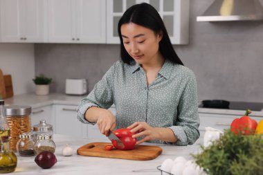 Yemek pişirme süreci. Güzel bir kadın mutfakta beyaz tezgahta dolma biber kesiyor.