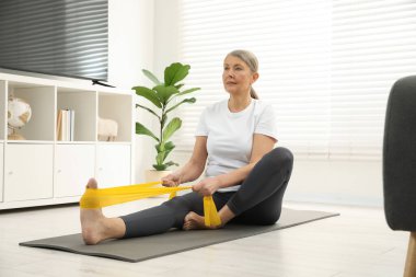 Son sınıf öğrencisi kadın evde spor yaparken lastikli bant takıyor.